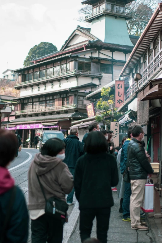 a group of people walking down a busy sidewalk next to tall buildings