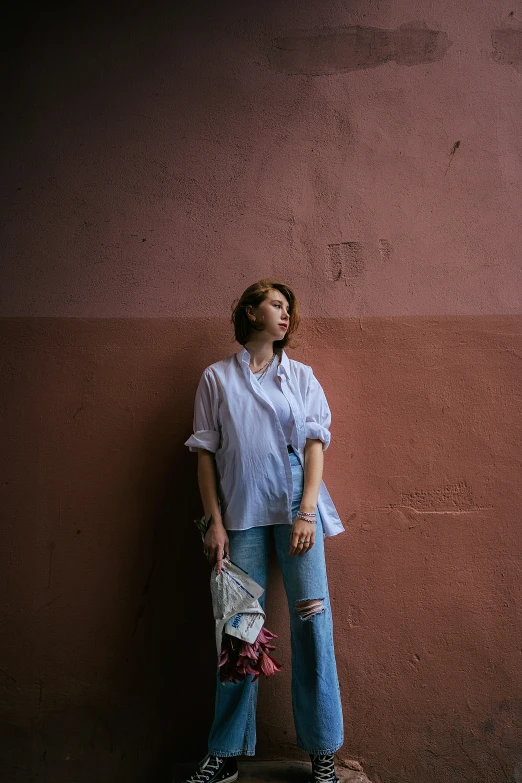 a woman wearing ripped jeans, a white blouse and black sneakers