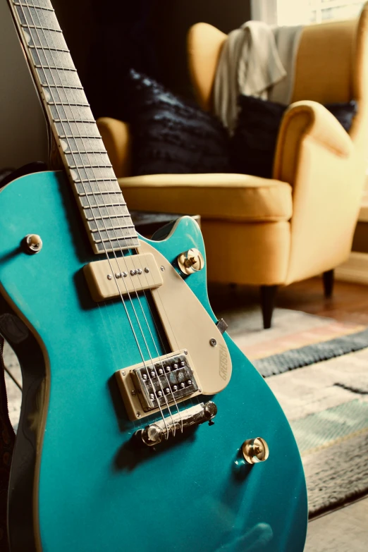 there is a blue electric guitar sitting by a chair