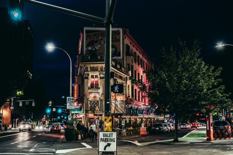 a street corner at night with lights on and various cars