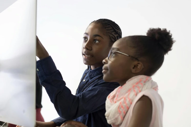 a boy and a girl playing with the computer screen