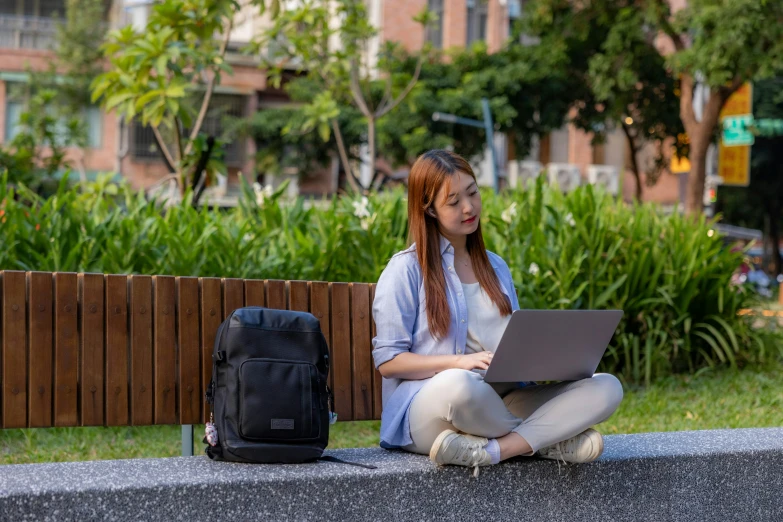 girl sitting on the side of a street using her lap top