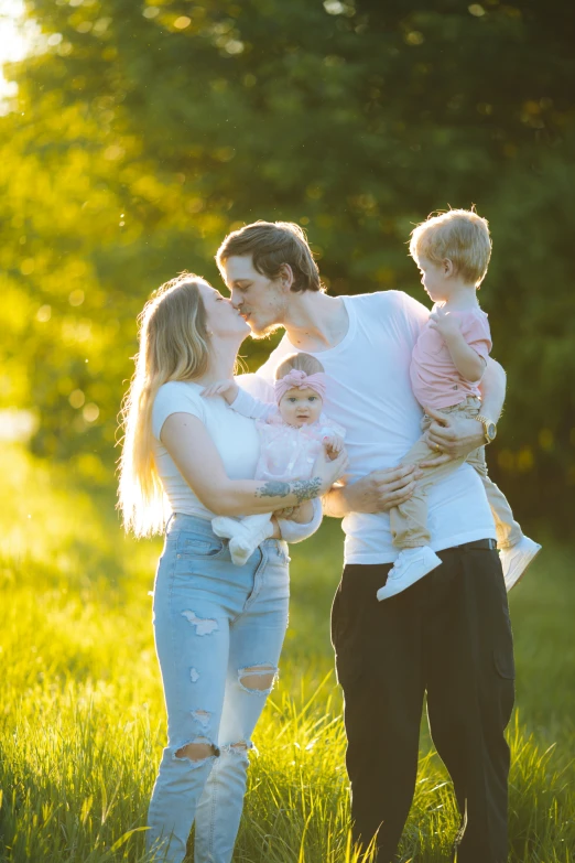 young adults, one holding small baby girl in field