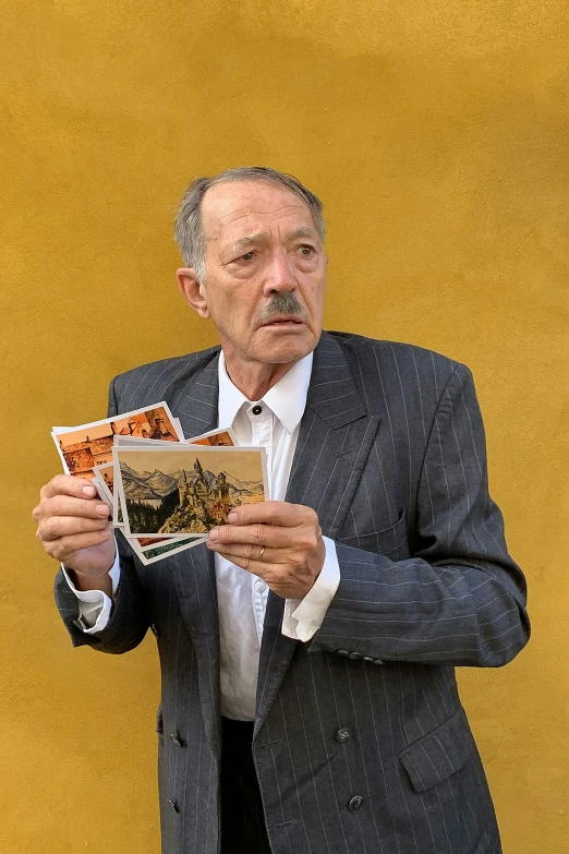 an old man holding a copy of a novel in his hands