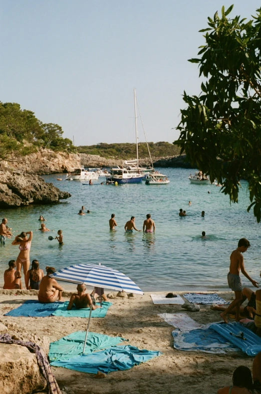 a number of people swimming and sitting on top of a beach