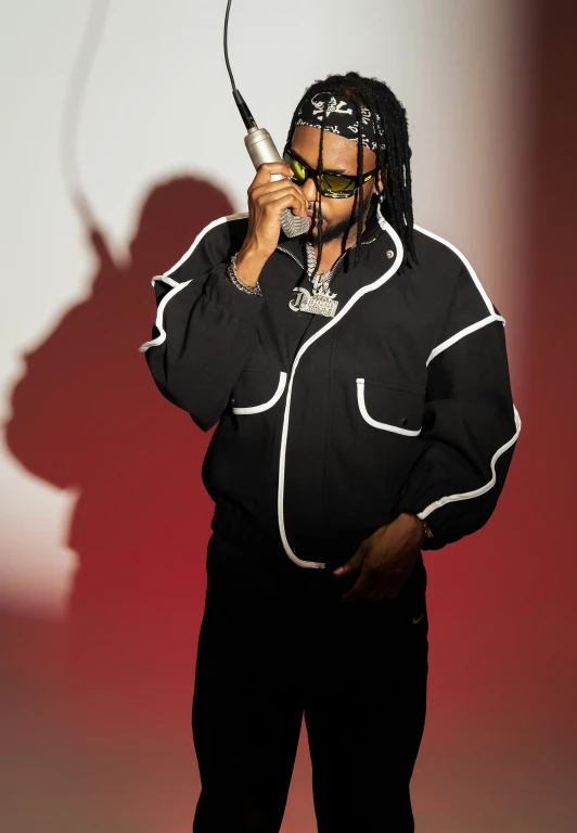 a man with dreadlocks wearing a black jacket and holding a microphone in his hand