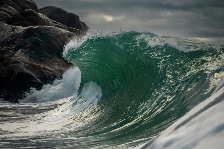 the wave is crashing towards the rocky shoreline