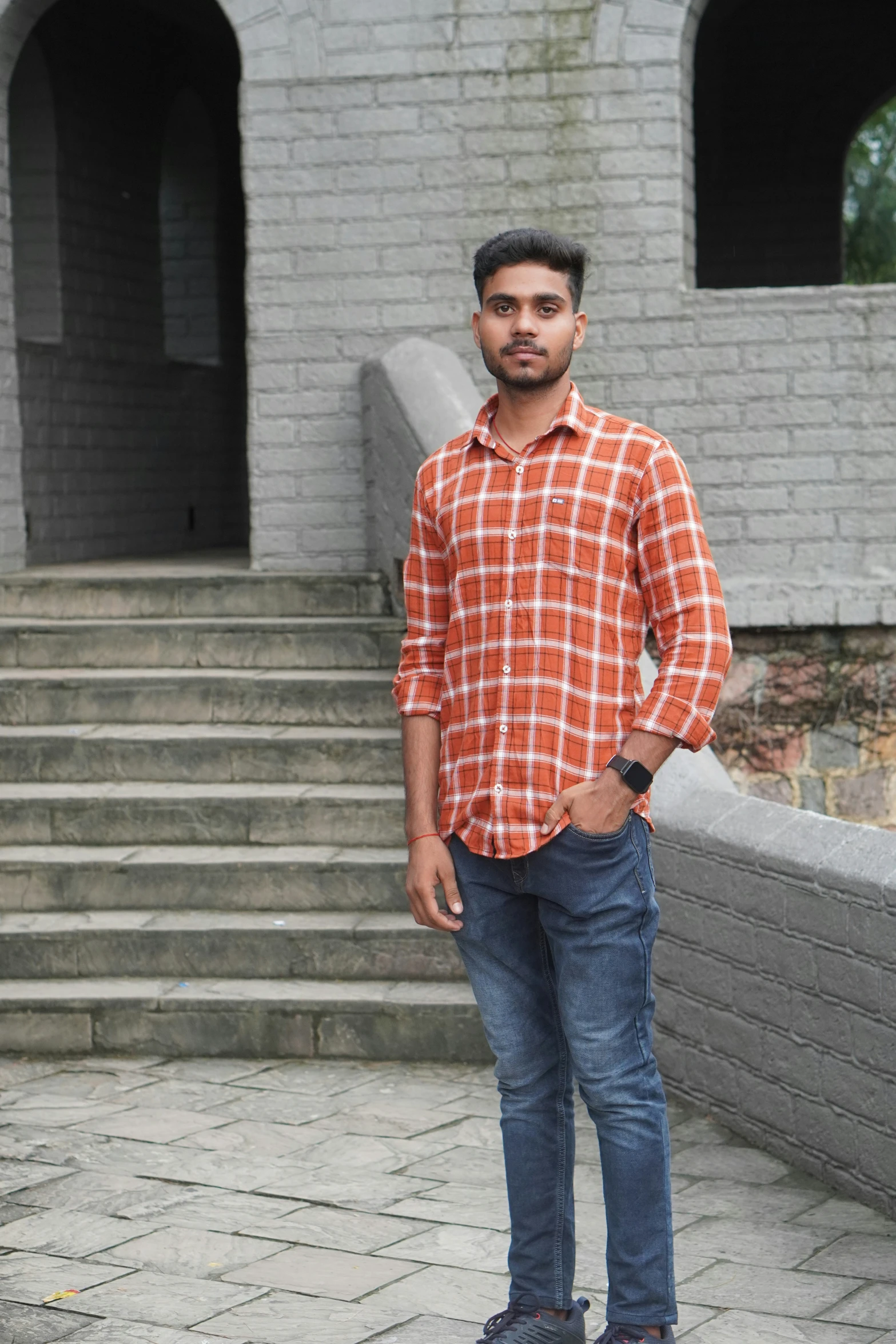 a man stands by some steps wearing an orange shirt