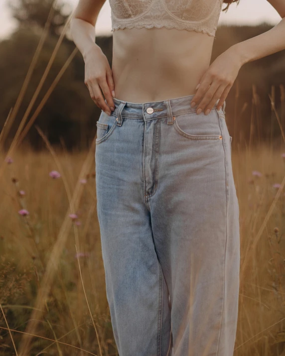 the woman wears wide legged jeans in the field