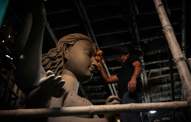 a statue of a young child sitting on top of a metal bar