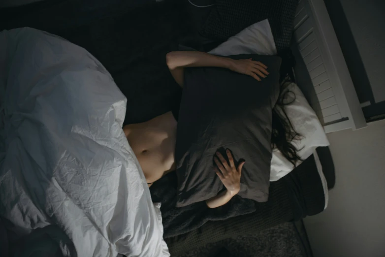 a man laying in bed with a gray pillow under his arm