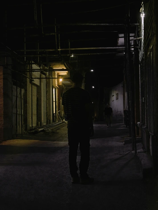 a man standing on the sidewalk under the street light at night