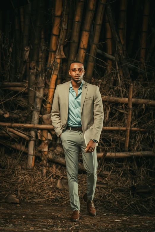 a man wearing a suit standing in front of a bamboo tree