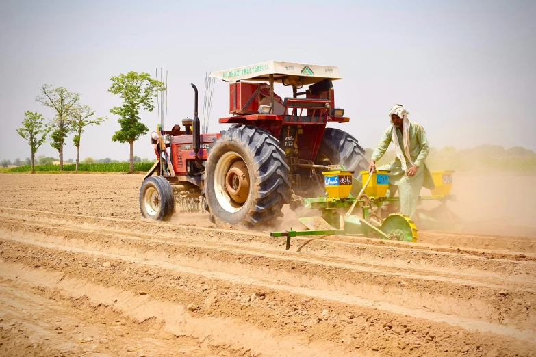 tractor and cultor in field, with dust blowing from the ground