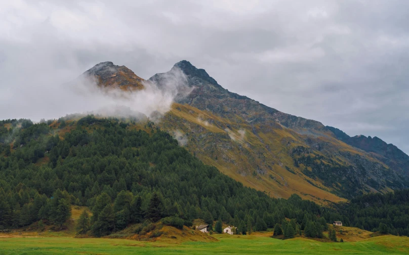 a mountain is behind some foggy, grassy hills