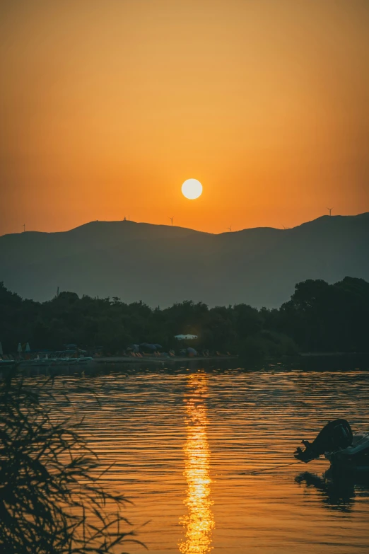 some water and trees at sunset with the sun setting