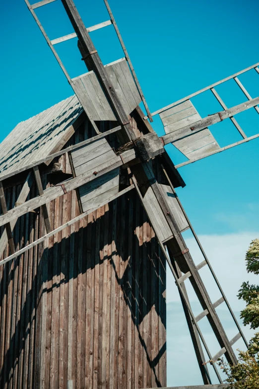 an old fashioned wind mill sits under a blue sky