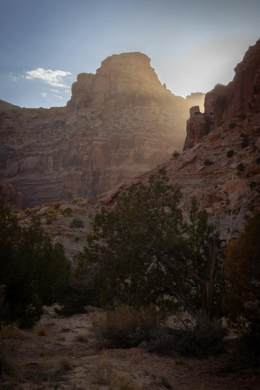 the sun shining through the mountains with rocks in the distance