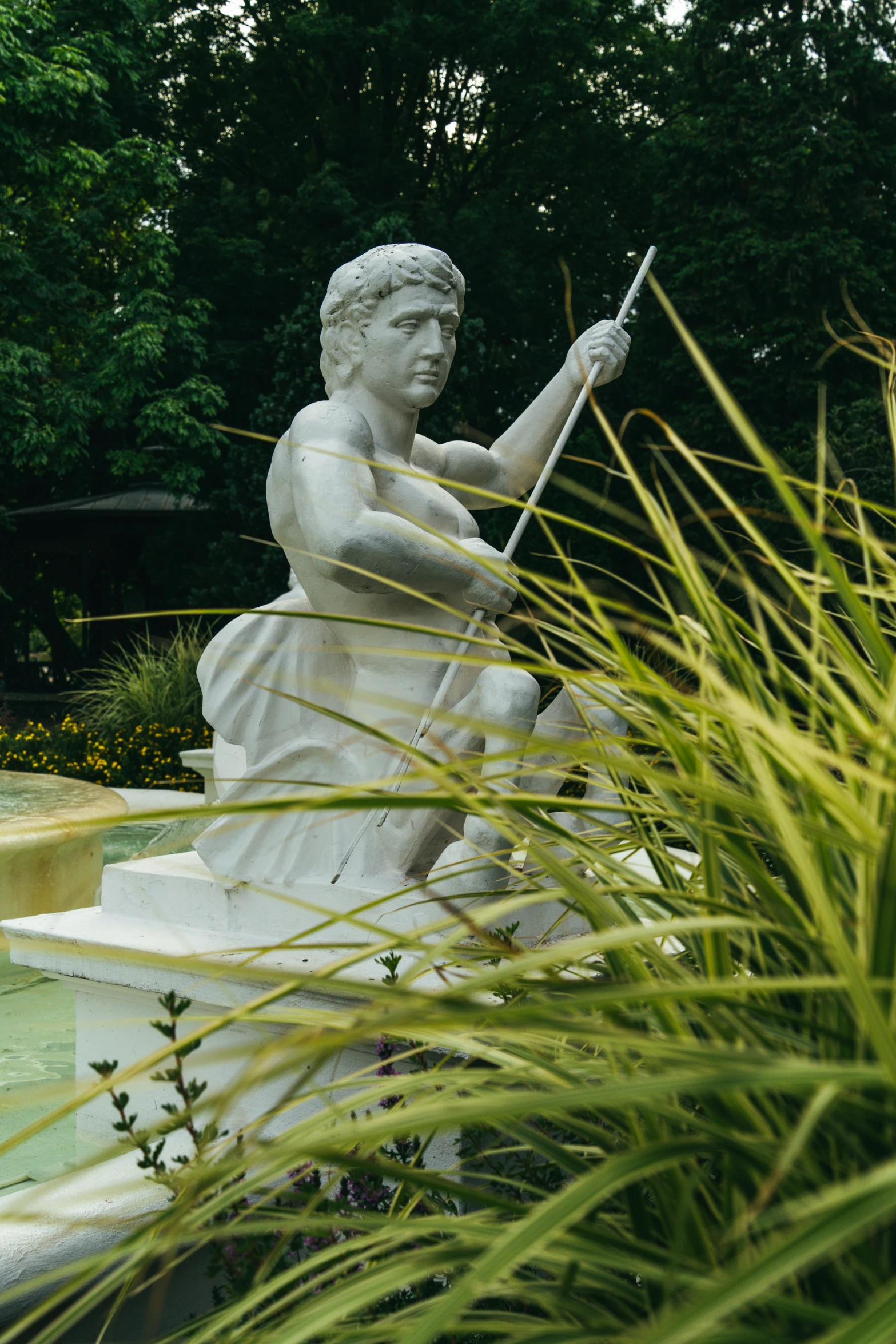 a statue holding an umbrella next to some grass