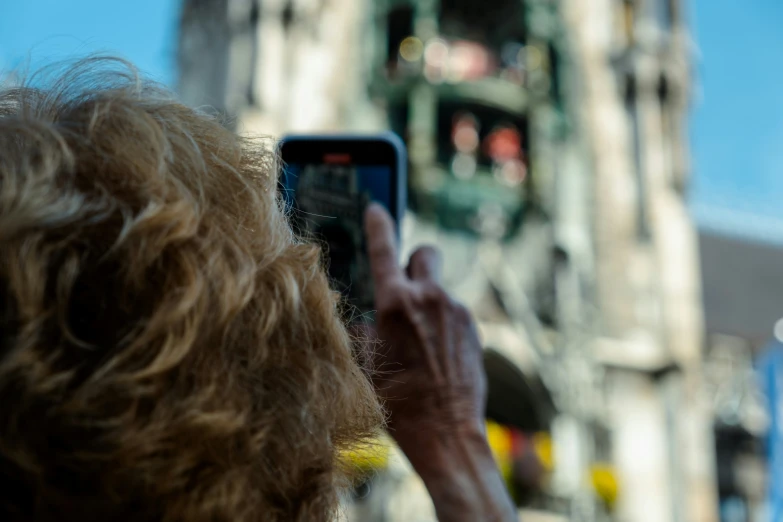 person taking pictures with their cell phone on the street