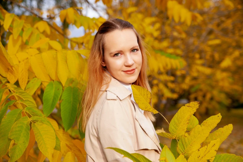 an attractive woman with long red hair standing near trees