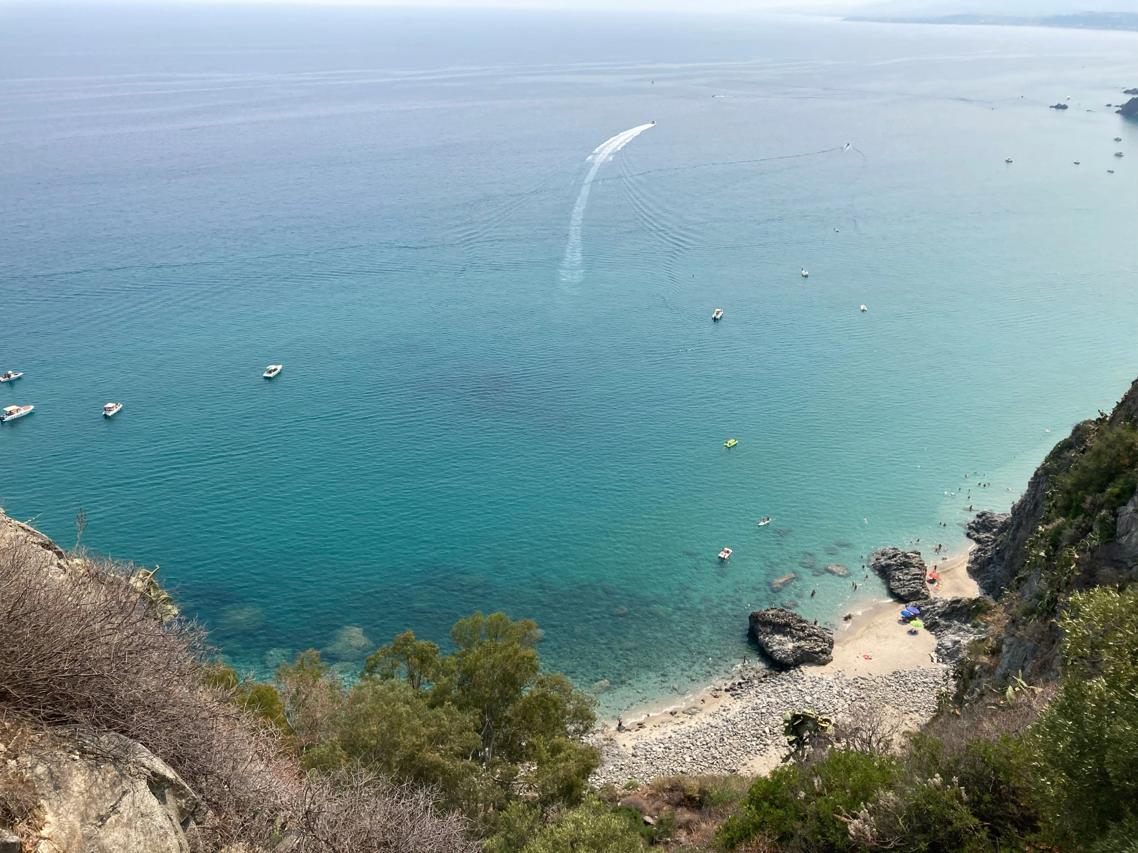 boats are parked on the beach as people swim