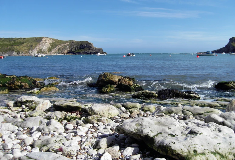 boats are sitting in the water near rocky beach