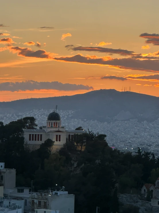 the city is shown as a sunset approaches over mountains