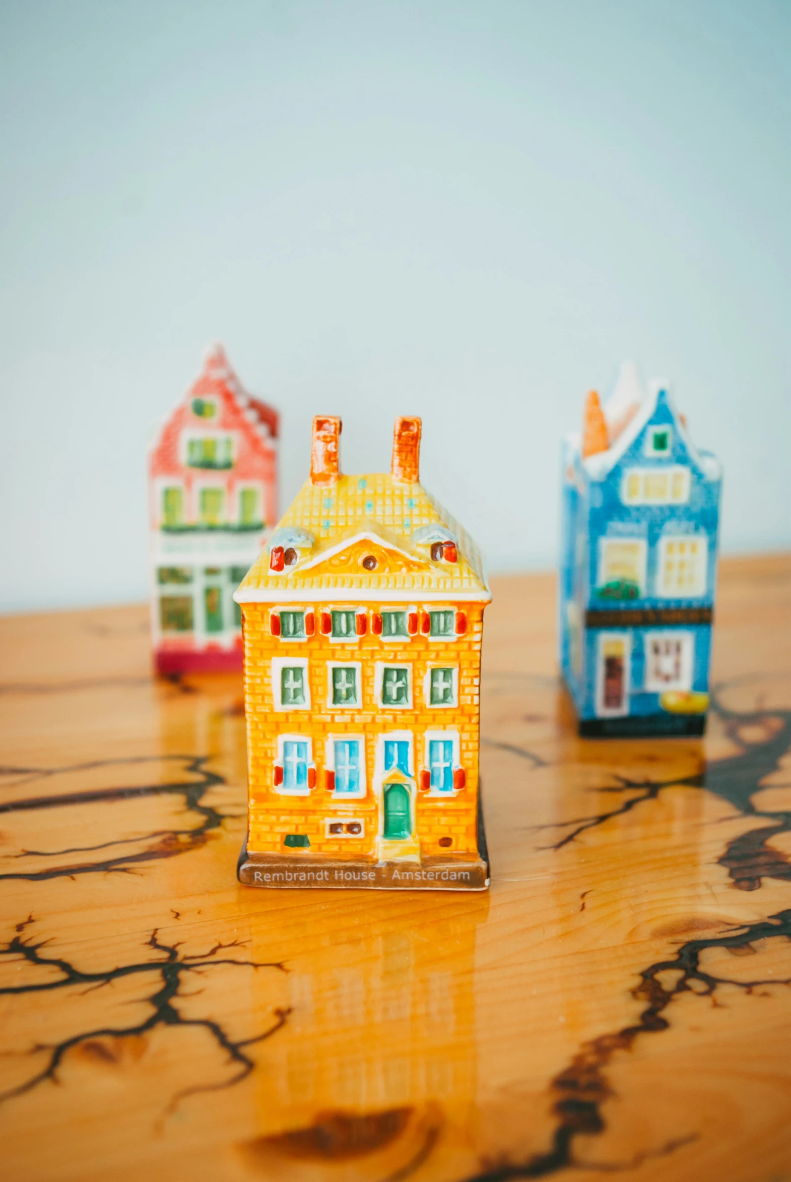 three miniature houses are on a wooden surface