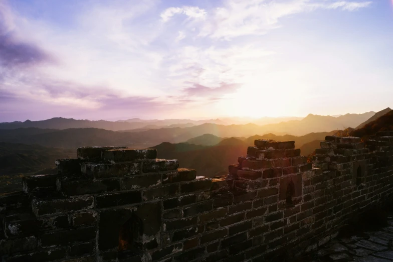 the sun setting over a huge wall made of stone