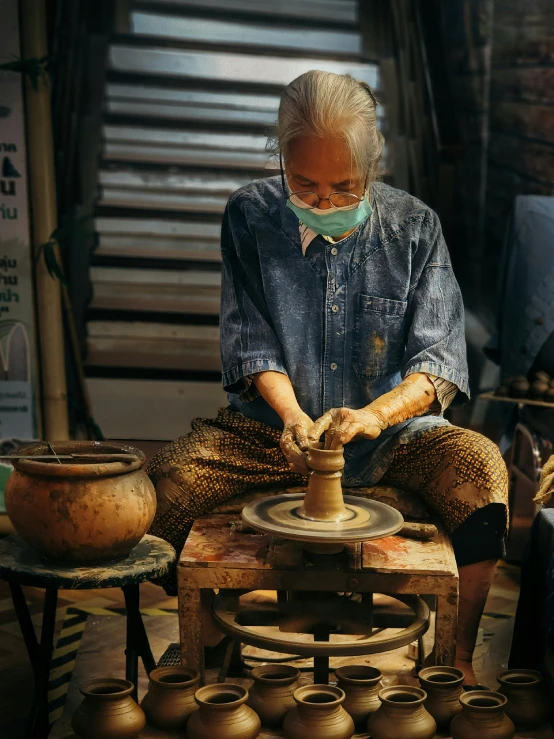 a woman working with a pottery wheel in a shop