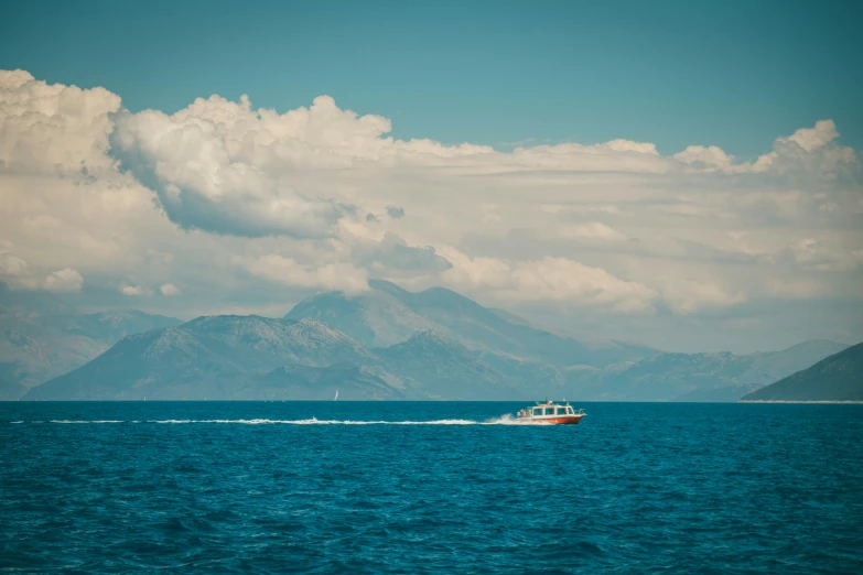 a boat in the open water with mountains in the background