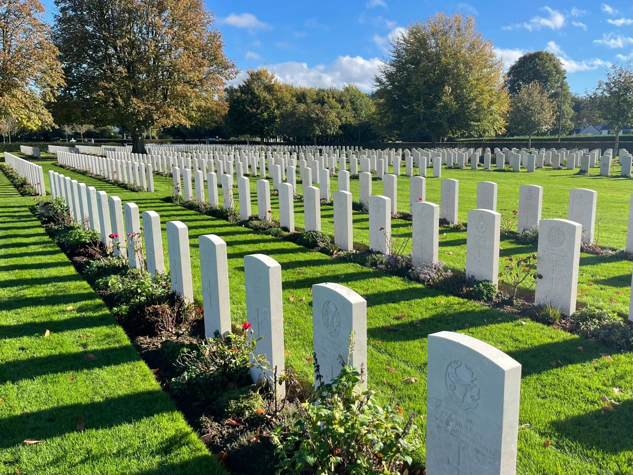 a long line of cement headstones in a grassy area