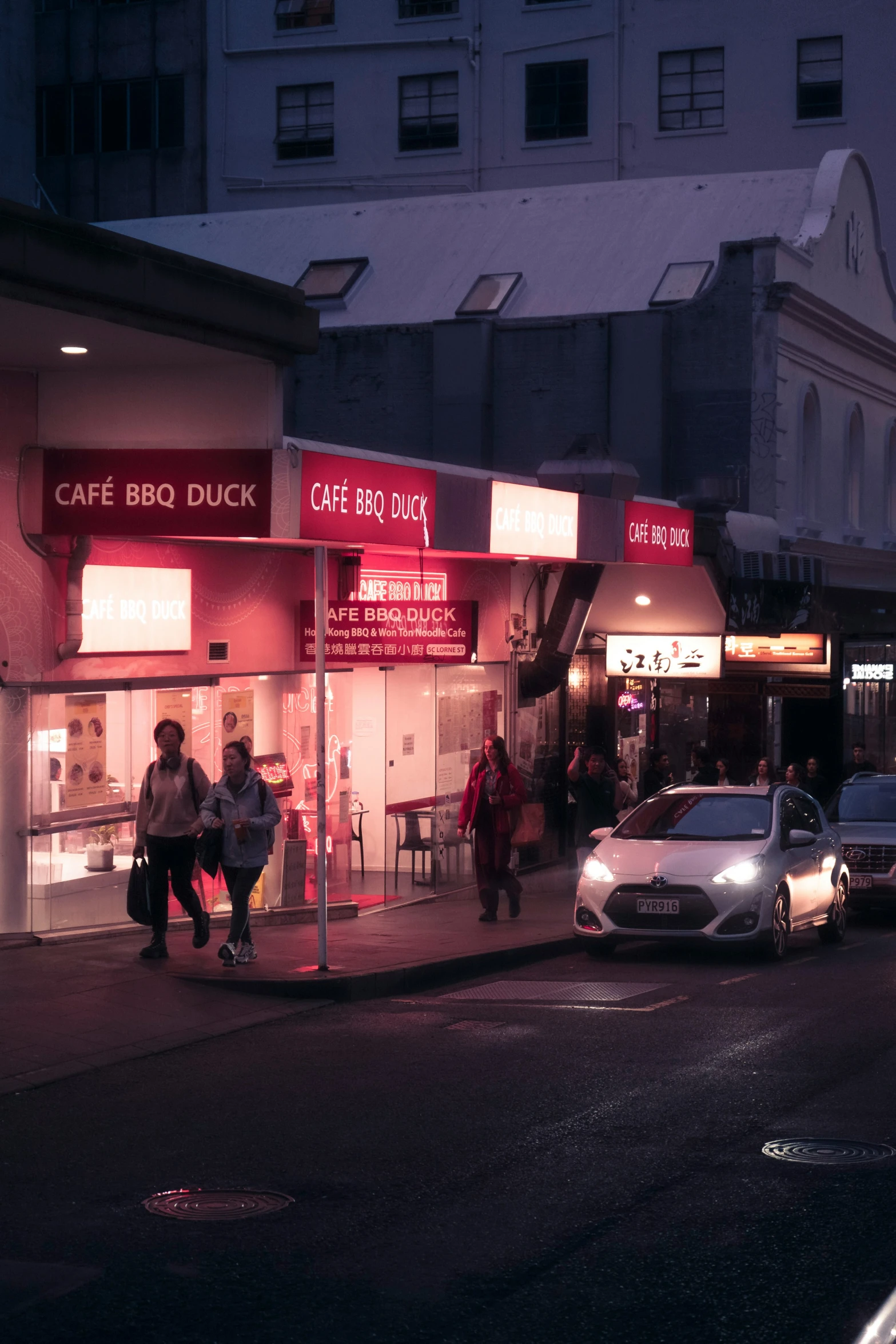 a woman walking down a street past a restaurant