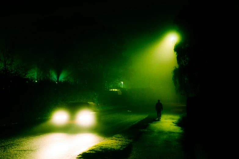 a person walks down the street at night by some cars