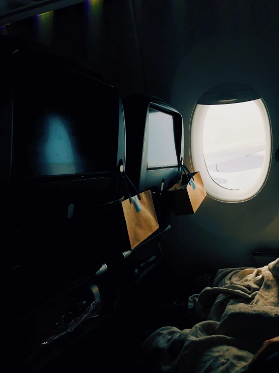 the window of an airplane shows a view of the bed and window