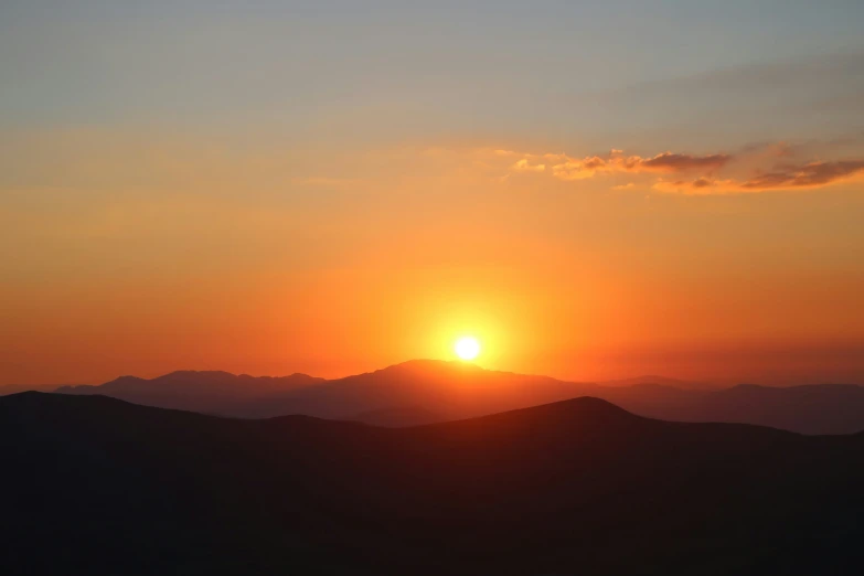 the sun sets over the mountain tops over mountains