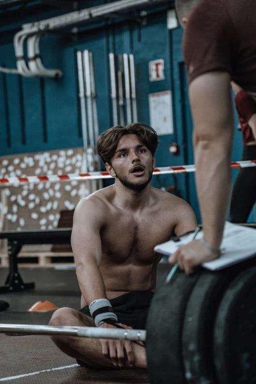 man sitting on floor next to a machine with his shirt off