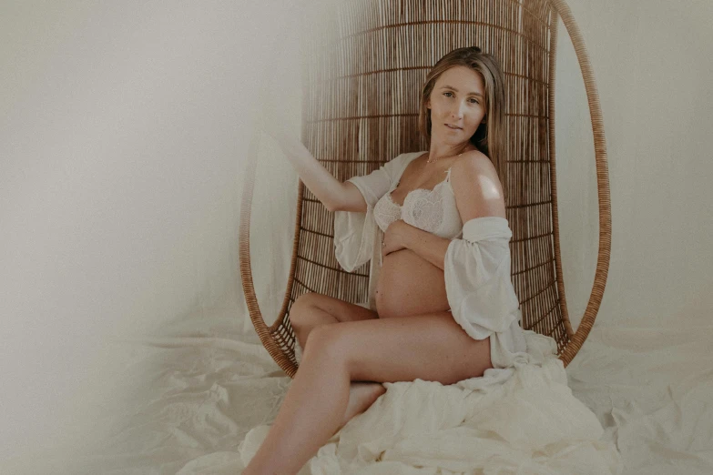 a woman is sitting in a wicker chair on a bed