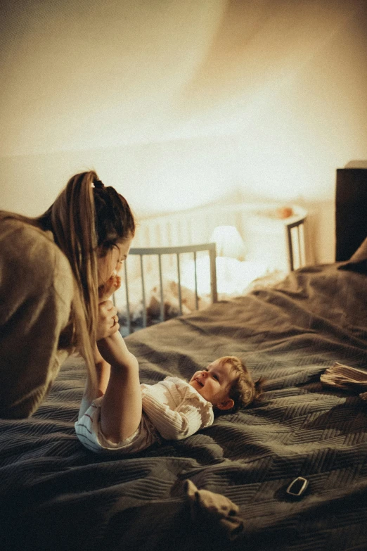 a little girl laying on a bed next to a woman