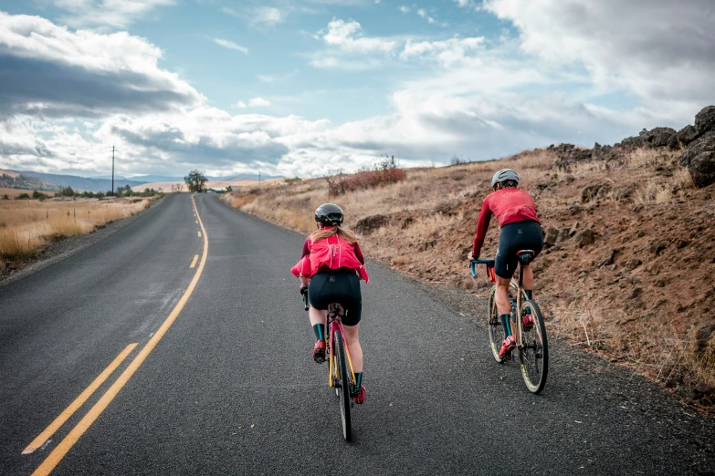 two people riding bikes on an open country road