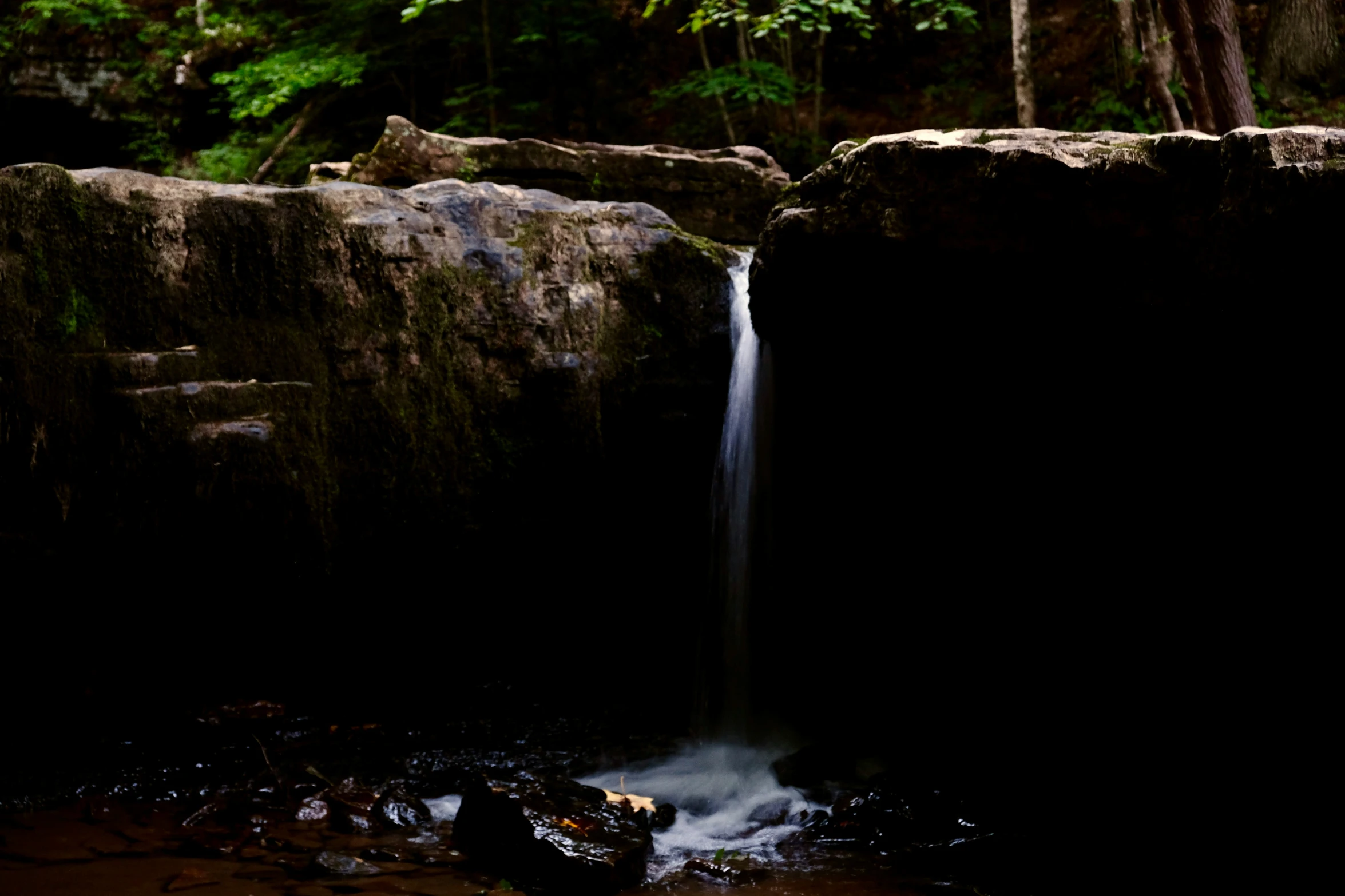 a waterfall is in the middle of some large rocks