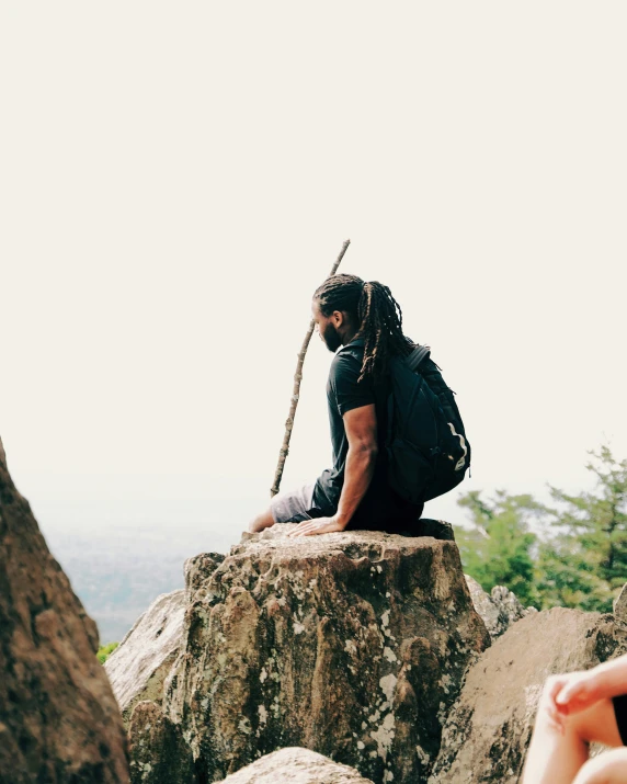 a person sitting on a rock with a backpack