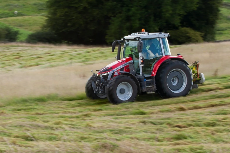 a tractor is driving on the side of a grassy field