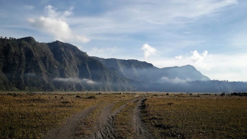 a truck traveling down a dirt road surrounded by mountains