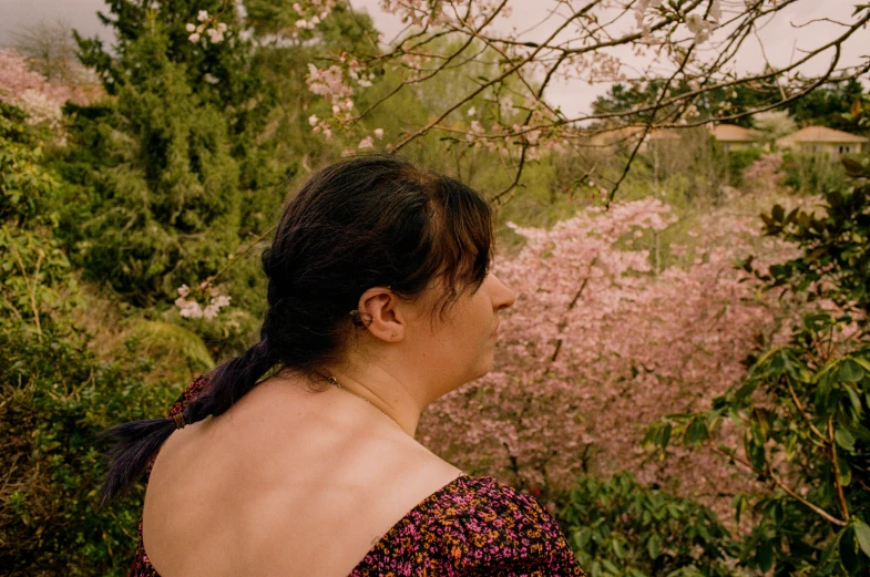 a woman in floral top looking out over a wooded area