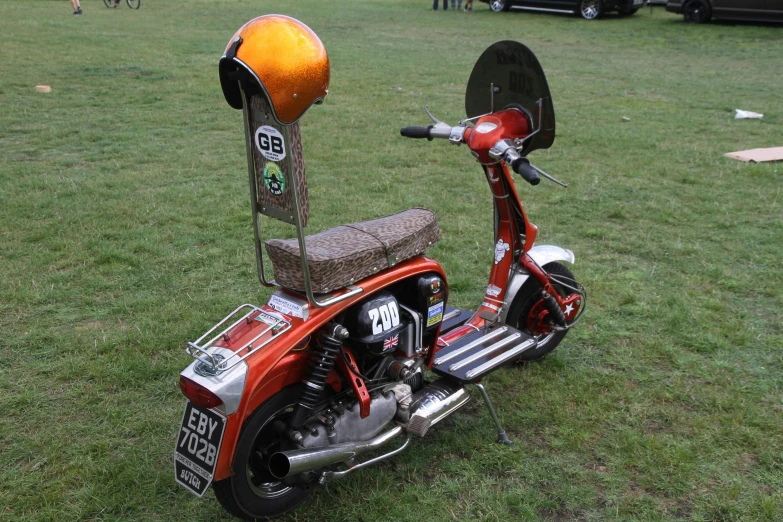 a red motor scooter with an orange helmet sitting on it