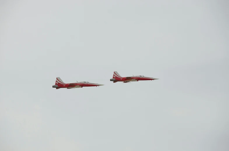 two jets are flying in formation in an air field