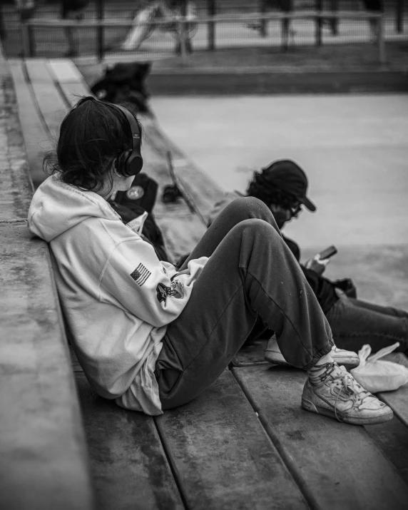 the young woman sits on the side of the water with her headphones up