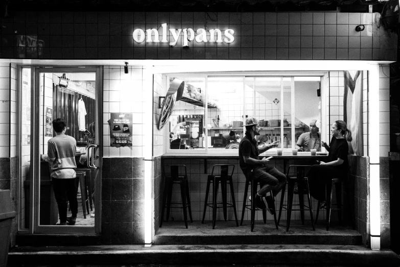 two people are having drinks outside of a restaurant at night